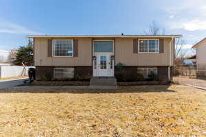 Split foyer home with brick siding, entry steps, a front lawn, and fence