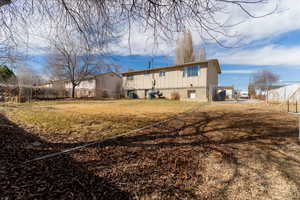 Rear view of house featuring fence, a yard, and a gate