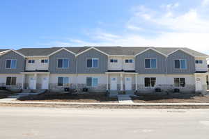 Townhome / multi-family property with stone siding, central AC unit, and board and batten siding