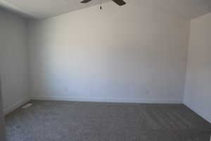 Carpeted spare room featuring visible vents, baseboards, and a ceiling fan