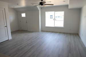 Unfurnished living room with plenty of natural light, wood finished floors, visible vents, and ceiling fan