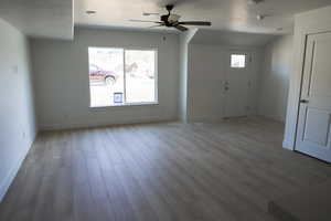 Interior space with wood finished floors, a ceiling fan, baseboards, and a textured ceiling