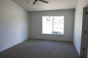 Empty room featuring dark colored carpet, baseboards, a textured ceiling, and ceiling fan