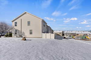 Snow covered house featuring a residential view and fence