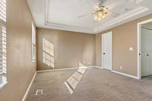 Carpeted spare room with ceiling fan, baseboards, and a tray ceiling