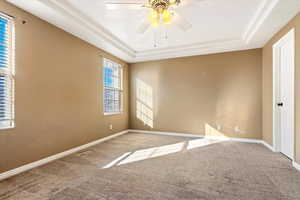 Spare room with a ceiling fan, carpet, baseboards, and a tray ceiling