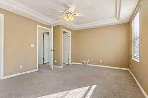 Unfurnished bedroom with a ceiling fan, a tray ceiling, carpet floors, and baseboards