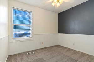 Carpeted empty room with wainscoting, and a healthy amount of sunlight