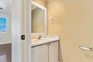 Bathroom with vanity, wood finished floors, and baseboards