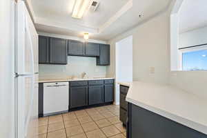 Kitchen featuring visible vents, a sink, white appliances, light countertops, and light tile patterned floors