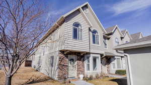 Multi unit property with stone siding, roof with shingles, and stucco siding