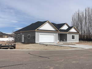 View of front of house featuring an attached garage, driveway, and fence