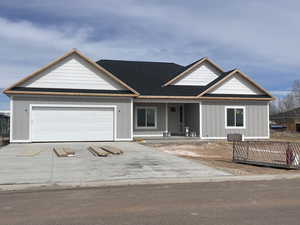 View of front of home featuring roof with shingles, a porch, concrete driveway, a garage, and board and batten siding