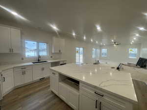 Kitchen with dark wood finished floors, white cabinetry, a ceiling fan, and a sink