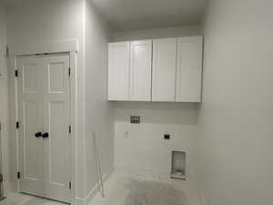 Clothes washing area featuring baseboards, cabinet space, hookup for an electric dryer, and washer hookup