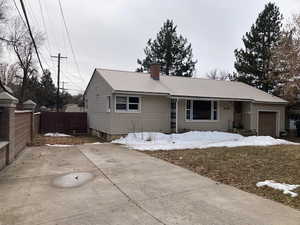 Single story home featuring an attached garage, metal roof, fence, and a chimney