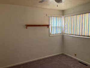 Carpeted spare room with baseboards, visible vents, a textured ceiling, and a ceiling fan