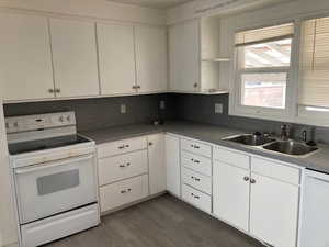 Kitchen with a sink, wood finished floors, white cabinets, white appliances, and open shelves