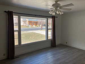 Unfurnished dining area with a ceiling fan, baseboards, and wood finished floors