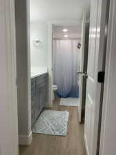 Full bath featuring toilet, vanity, a shower with curtain, and wood finished floors