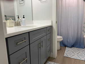 Full bath with vanity, toilet, and wood finished floors