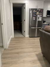 ADU Kitchen with baseboards, light countertops, light wood-style flooring, appliances with stainless steel finishes, and white cabinetry