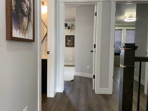 Hallway featuring dark wood-type flooring, baseboards, and a textured ceiling