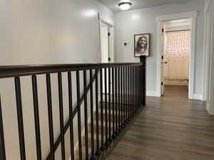 Hallway with dark wood finished floors, an upstairs landing, and baseboards