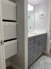 Bathroom with toilet, vanity, baseboards, and wood finished floors