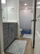Bathroom featuring vanity, a shower with shower curtain, wood finished floors, recessed lighting, and toilet