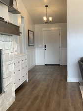 Foyer entrance featuring a chandelier, a wainscoted wall, and dark wood-type flooring