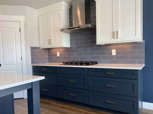 Kitchen featuring light countertops, wall chimney range hood, and stainless steel gas cooktop