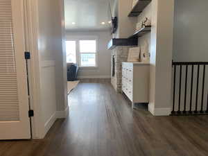 Interior space with a textured ceiling, dark wood-style floors, white cabinetry, light countertops, and baseboards