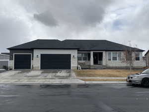 View of front of house featuring concrete driveway, an attached garage, stone siding, and roof with shingles