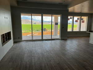 Unfurnished living room featuring dark wood-style floors, a mountain view, baseboards, and plenty of natural light