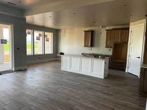 Kitchen with dark wood-style flooring, baseboards, and a center island