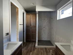 Full bath featuring vanity, tiled shower, and wood finished floors