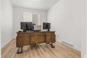 Office space with wood finished floors, visible vents, and baseboards
