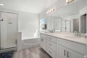 Bathroom with double vanity, a stall shower, a garden tub, and a sink