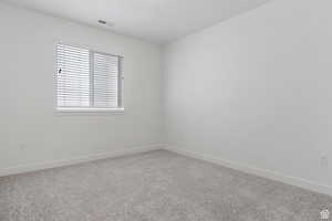 Carpeted spare room featuring visible vents and baseboards