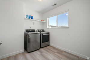 Washroom featuring visible vents, baseboards, laundry area, and washing machine and clothes dryer