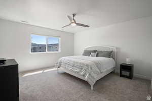 Carpeted bedroom with baseboards, visible vents, and ceiling fan