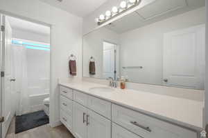 Bathroom featuring shower / bathtub combination with curtain, toilet, and vanity