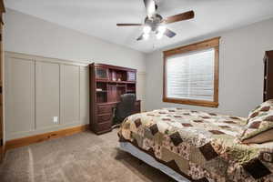 Bedroom with light carpet, ceiling fan, and a desk