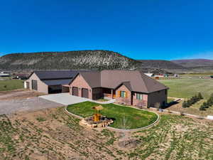 View of front facade featuring driveway, a mountain view, an attached garage, brick siding, and a front yard