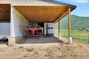 View of patio with a mountain view, an exterior structure, a carport, a view of rural / pastoral area, and an outdoor structure