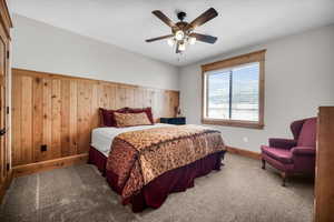Bedroom featuring carpet flooring, ceiling fan, and wood walls