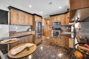 Kitchen featuring appliances with stainless steel finishes, dark stone counters, backsplash, a peninsula, and recessed lighting