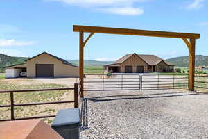 View of yard with an outdoor structure, dirt driveway, a mountain view, a detached garage, and a pole building