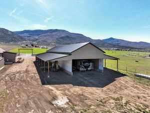 Exterior space featuring fence, an outdoor structure, a mountain view, a rural view, and dirt driveway